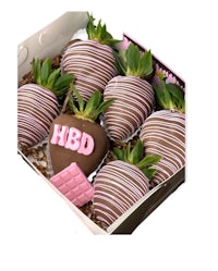 a box of chocolate covered strawberries with the word hbd